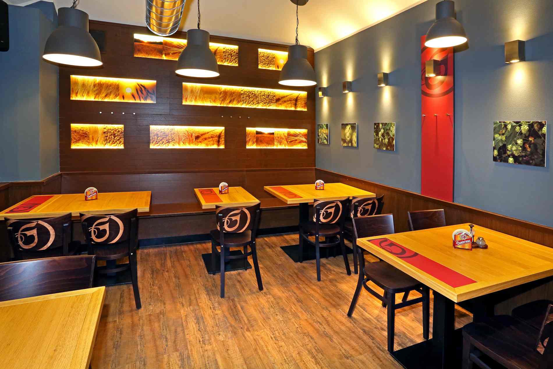 Interiér restaurace — dřevěné stoly a prosvětlené panely s ječmenem